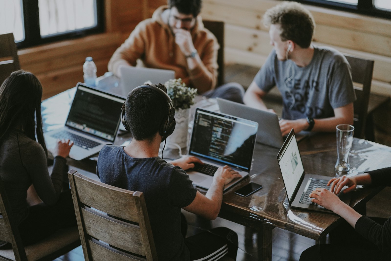 Time colaborando em volta de uma mesa com laptops